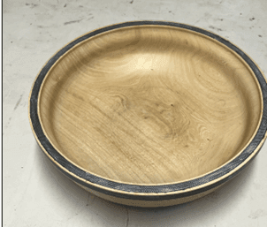 Round wooden bowl with a smooth finish and subtle wood grain patterns, placed on a white surface.